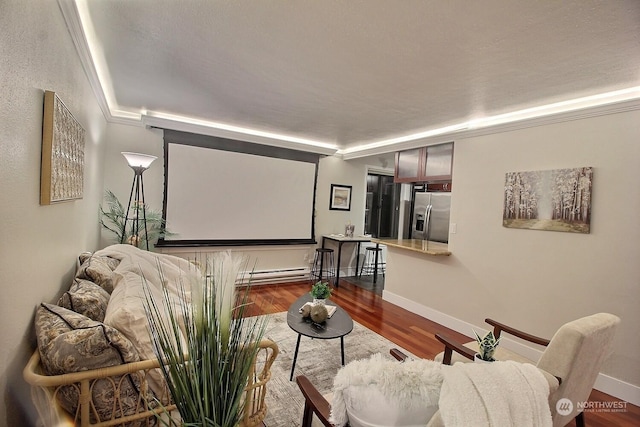 home theater featuring dark wood-type flooring, a baseboard radiator, and ornamental molding