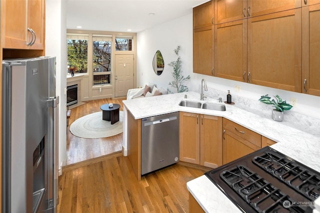 kitchen featuring kitchen peninsula, sink, stainless steel appliances, and light wood-type flooring