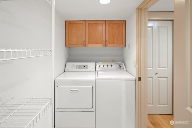 laundry area with separate washer and dryer, cabinets, and light wood-type flooring