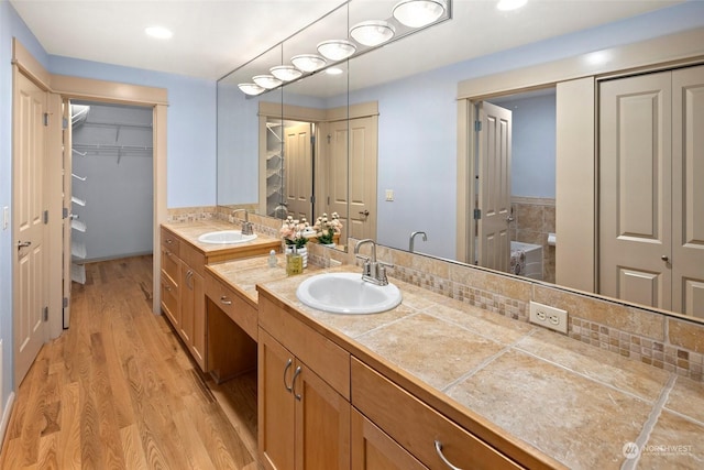 bathroom featuring hardwood / wood-style flooring, vanity, and decorative backsplash