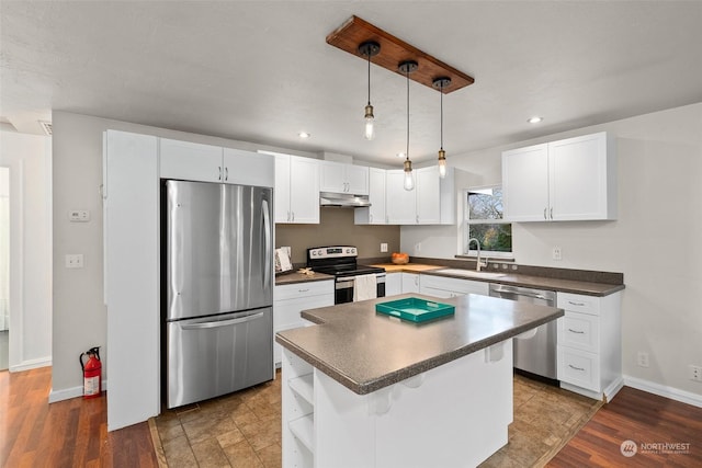 kitchen with sink, a center island, dark wood-type flooring, and appliances with stainless steel finishes