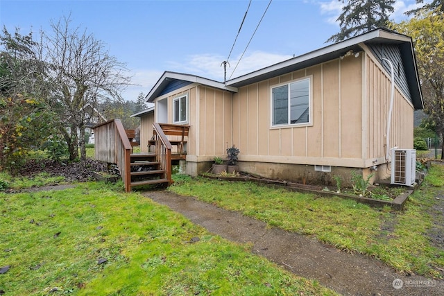 view of side of property with a yard, cooling unit, and a wooden deck