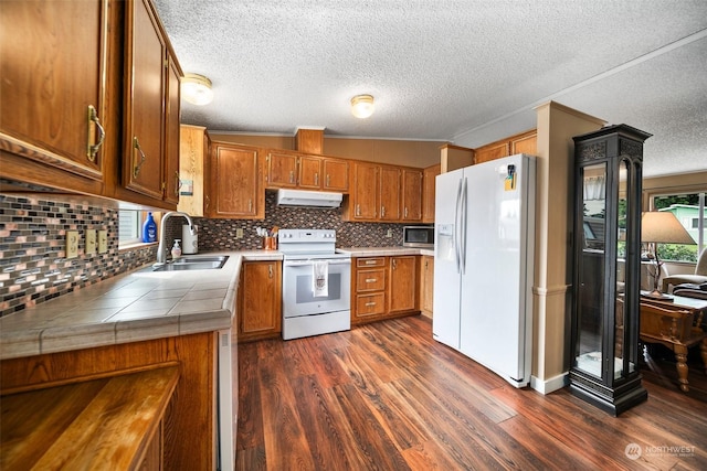 kitchen featuring lofted ceiling, backsplash, white appliances, sink, and dark hardwood / wood-style floors