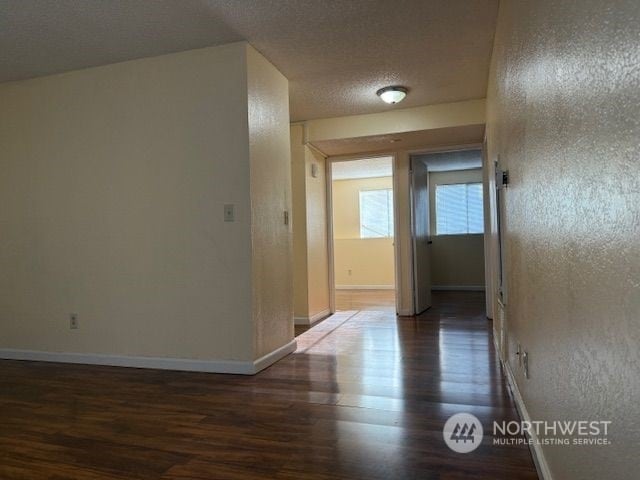 corridor featuring a textured ceiling and dark hardwood / wood-style floors