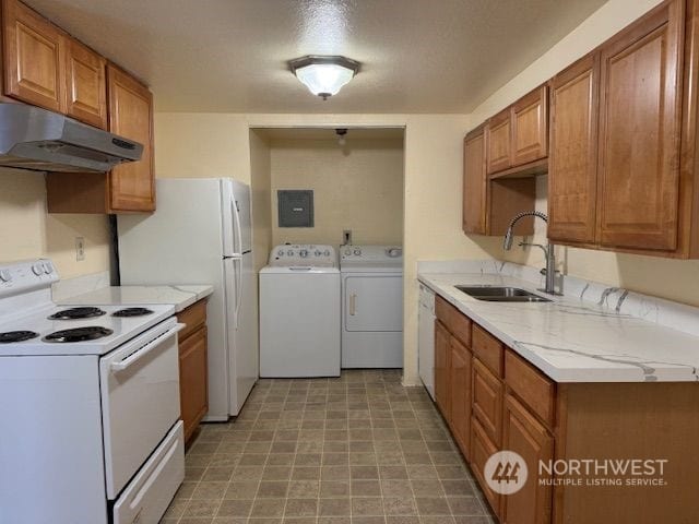 kitchen featuring white appliances, electric panel, sink, separate washer and dryer, and light stone counters