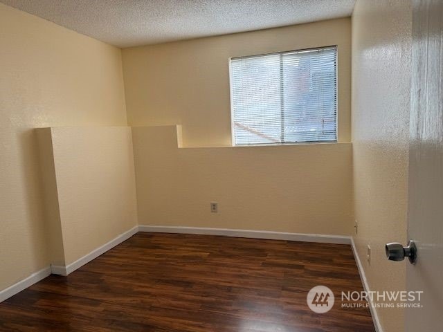 unfurnished room featuring a textured ceiling and dark wood-type flooring