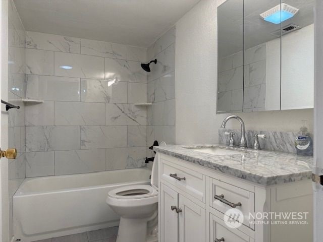 full bathroom featuring tile patterned flooring, vanity, tiled shower / bath combo, and toilet