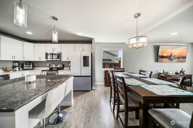 kitchen with decorative light fixtures, white cabinetry, and appliances with stainless steel finishes