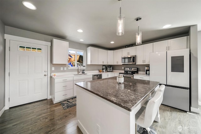 kitchen featuring a center island, sink, stainless steel appliances, dark hardwood / wood-style floors, and white cabinets