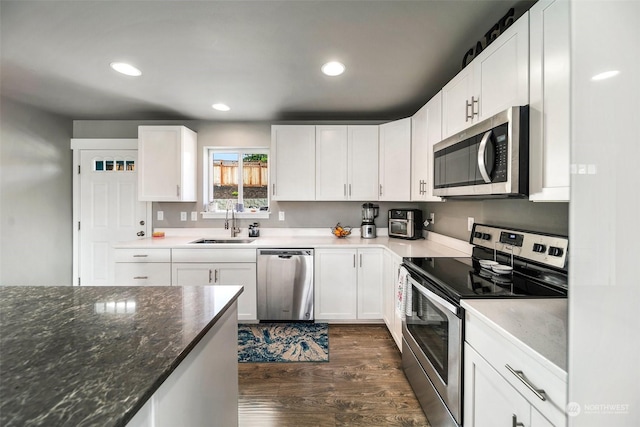 kitchen featuring sink, stainless steel appliances, dark hardwood / wood-style floors, dark stone counters, and white cabinets