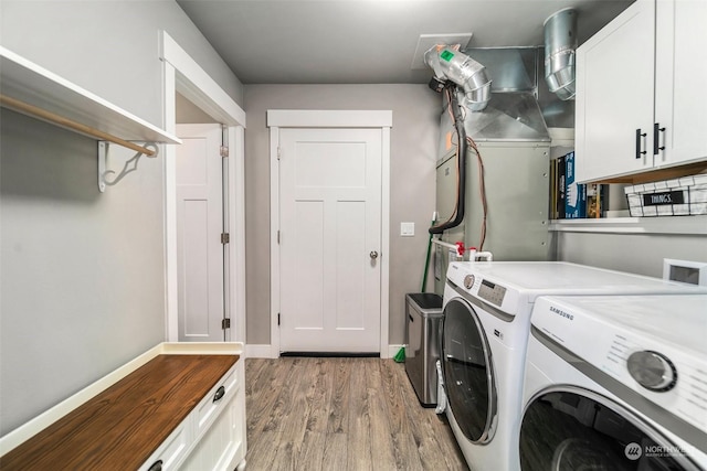 washroom featuring washing machine and dryer, cabinets, and hardwood / wood-style flooring