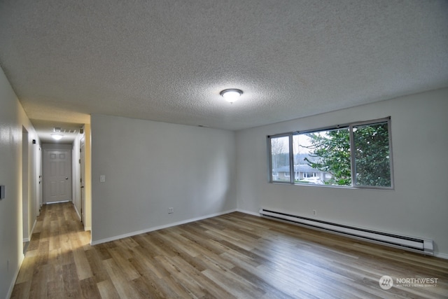 empty room featuring a textured ceiling, light hardwood / wood-style flooring, and a baseboard heating unit