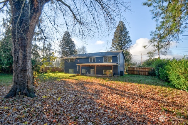 rear view of property with fence and a lawn