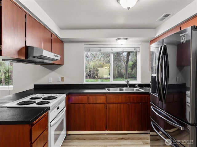 kitchen featuring dark countertops, black fridge with ice dispenser, under cabinet range hood, and white range with electric cooktop