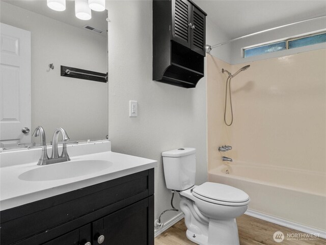 full bath featuring visible vents, toilet, vanity, wood finished floors, and  shower combination