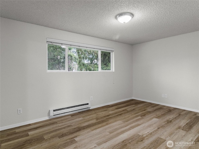 empty room with baseboard heating, light wood-style flooring, and baseboards