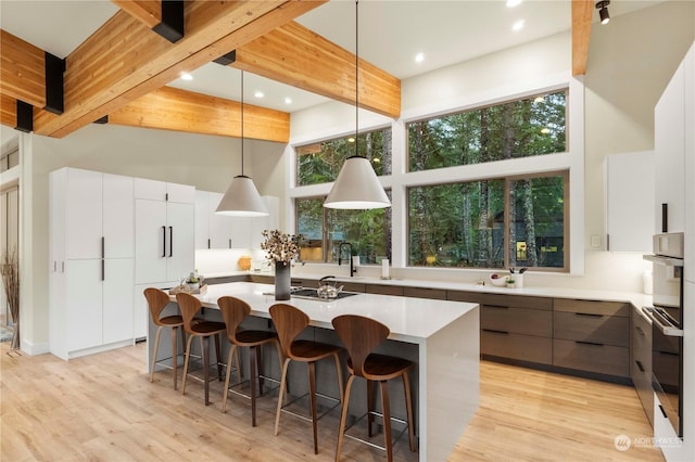 kitchen featuring beam ceiling, a center island, and white cabinetry