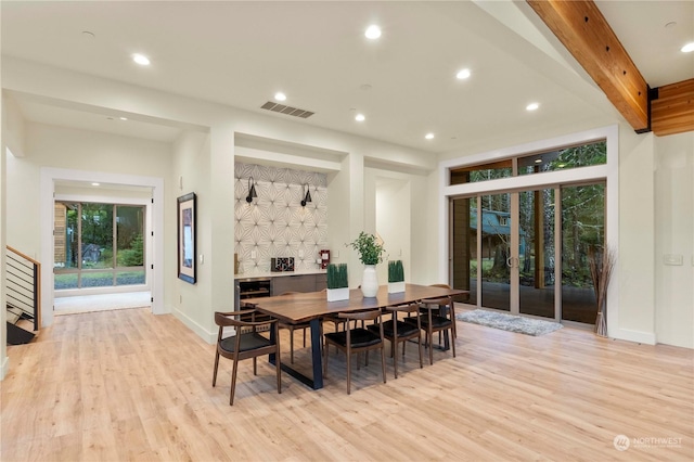 dining room with beam ceiling and light hardwood / wood-style floors