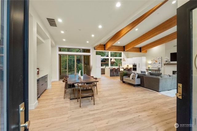 dining space featuring beam ceiling and light hardwood / wood-style flooring