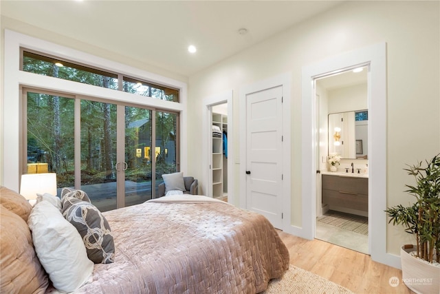 bedroom featuring access to exterior, ensuite bath, light hardwood / wood-style flooring, a spacious closet, and a closet