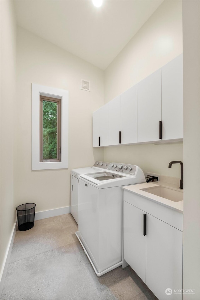 clothes washing area with cabinets, sink, and washing machine and clothes dryer