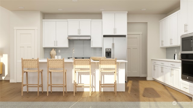 kitchen featuring white cabinets, a breakfast bar, decorative backsplash, and light hardwood / wood-style flooring