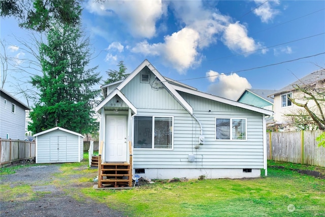 back of house with a lawn and a shed