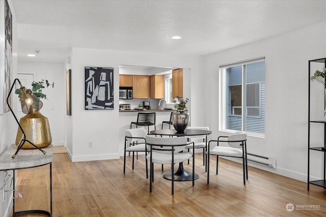 dining space with light wood-type flooring and sink