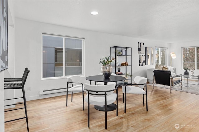 dining space with light wood-type flooring and a baseboard heating unit