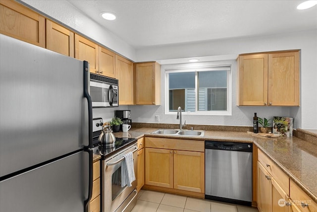 kitchen with light brown cabinets, sink, dark stone countertops, light tile patterned floors, and appliances with stainless steel finishes