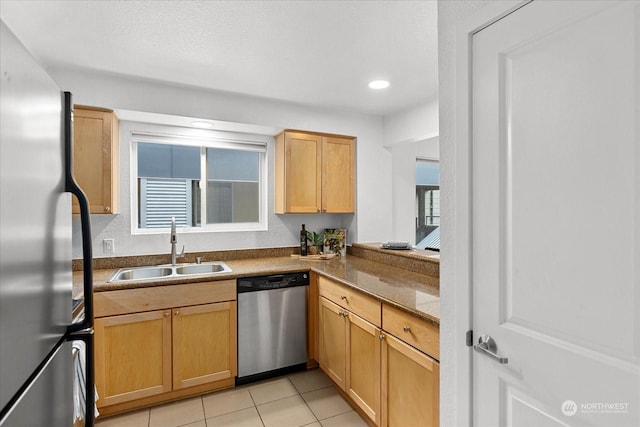 kitchen with light tile patterned flooring, stainless steel appliances, light stone counters, and sink