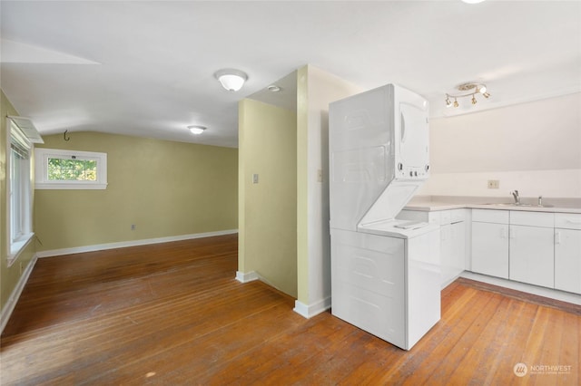 kitchen with white cabinets, light wood-type flooring, lofted ceiling, and stacked washer / drying machine