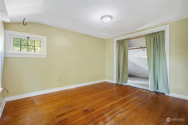 empty room featuring hardwood / wood-style floors and vaulted ceiling