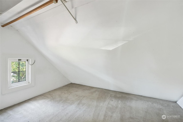 additional living space featuring light colored carpet and vaulted ceiling