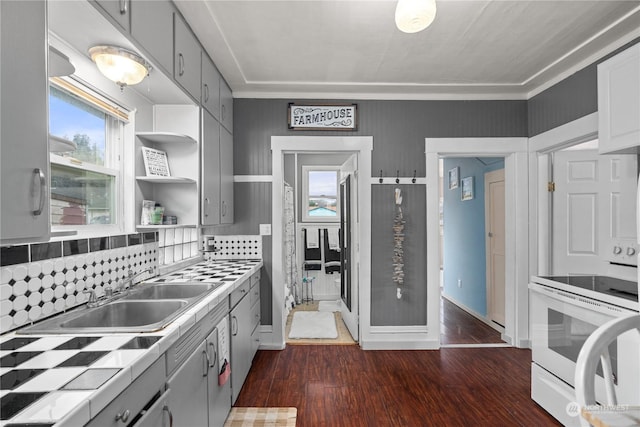 kitchen featuring tile countertops, dark wood-type flooring, decorative backsplash, gray cabinets, and white electric range oven