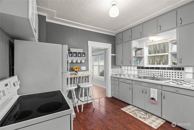 kitchen featuring sink, dark hardwood / wood-style floors, tile countertops, white appliances, and decorative backsplash