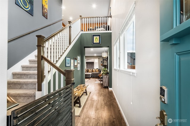 foyer with wood-type flooring and a towering ceiling