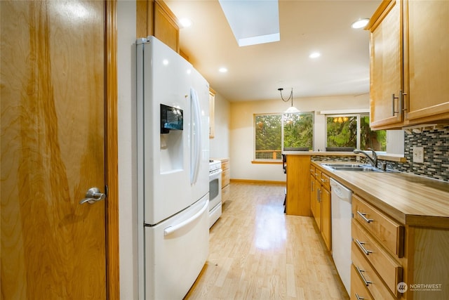 kitchen featuring a skylight, sink, decorative light fixtures, white appliances, and light wood-type flooring