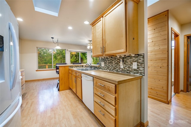 kitchen featuring white appliances, hanging light fixtures, a skylight, decorative backsplash, and light hardwood / wood-style floors