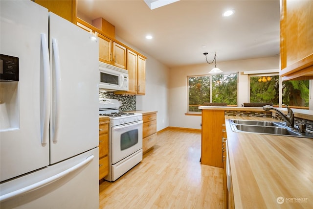 kitchen featuring sink, backsplash, light hardwood / wood-style floors, decorative light fixtures, and white appliances