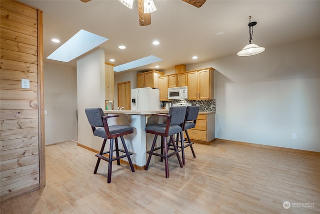 kitchen featuring light hardwood / wood-style floors, light brown cabinets, white appliances, and a skylight