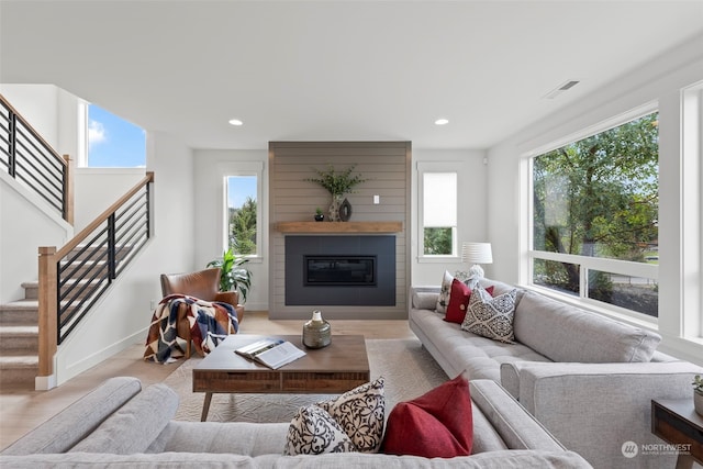 living room with a large fireplace and light hardwood / wood-style flooring