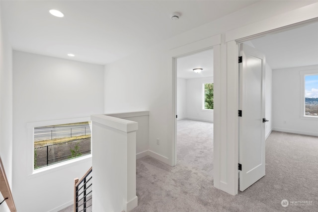 corridor featuring light colored carpet and a healthy amount of sunlight