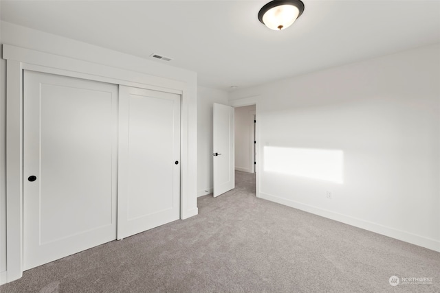 unfurnished bedroom with a closet and light colored carpet