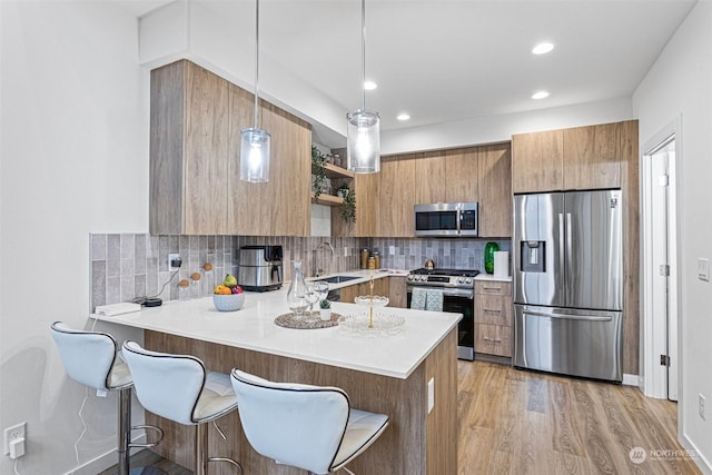 kitchen featuring stainless steel appliances, kitchen peninsula, pendant lighting, a kitchen bar, and backsplash