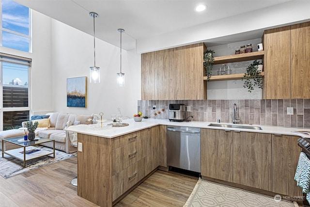 kitchen with dishwasher, kitchen peninsula, pendant lighting, sink, and tasteful backsplash