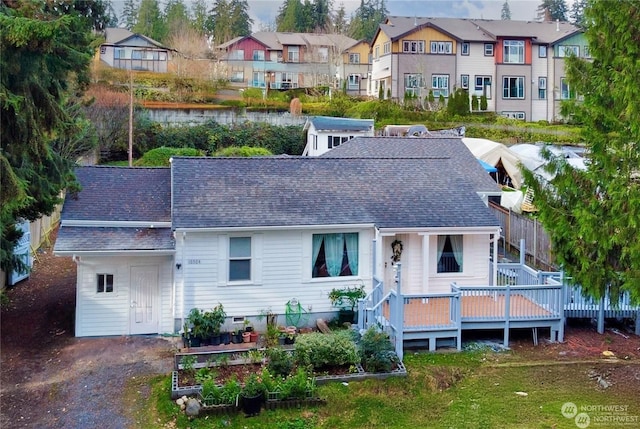 rear view of property with a residential view, a deck with water view, and roof with shingles