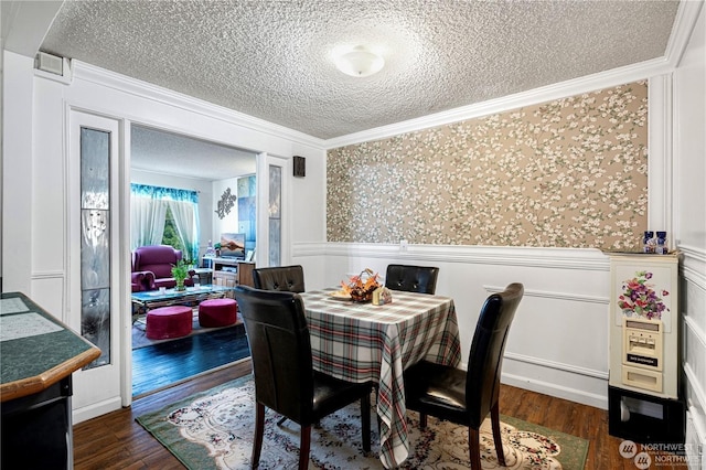 dining area with dark wood-style floors, ornamental molding, wainscoting, a textured ceiling, and wallpapered walls