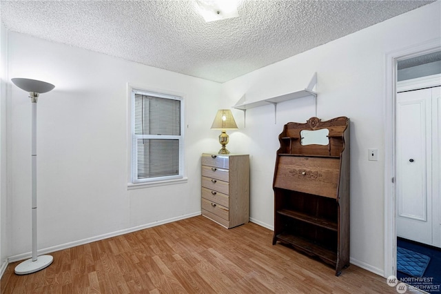 bedroom with a textured ceiling, baseboards, and wood finished floors