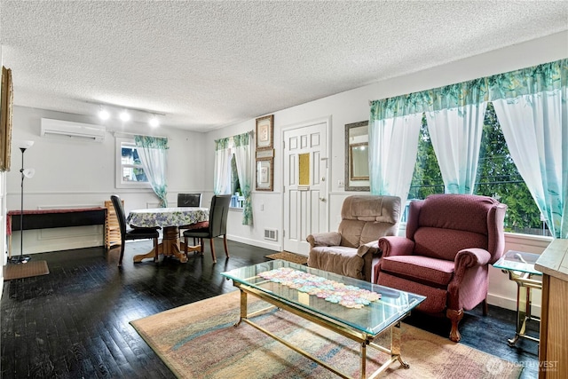 living room with baseboards, visible vents, wood-type flooring, a textured ceiling, and an AC wall unit